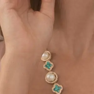 18K gold plated earrings featuring a luminous pearl and sparkling zirconia details. Finished with a delicate turquoise floral