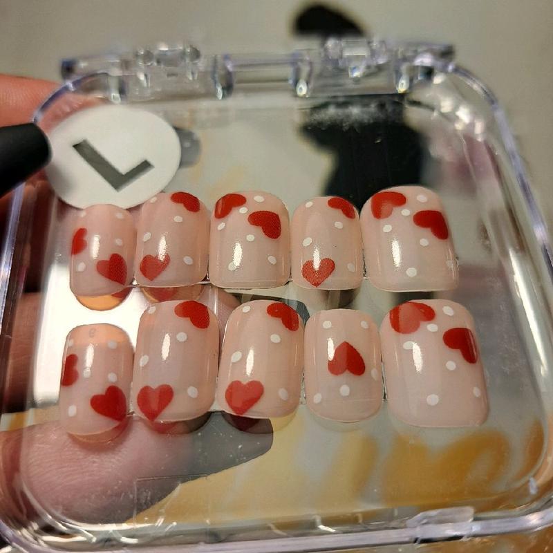 CMW (Dots of Love) press-on nails bring a playful romance to your fingertips. Featuring a nude natural base adorned with white polka dots and red hearts, these short square nails offer a classic yet fun look—exclusively in a size medium only."