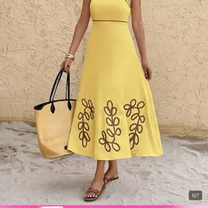 The Dress: A pale yellow, A-line midi dress featuring delicate spaghetti straps and a structured bodice. The standout elements are the chocolate brown contrast piping at the neckline and waist, along with the matching oversiz