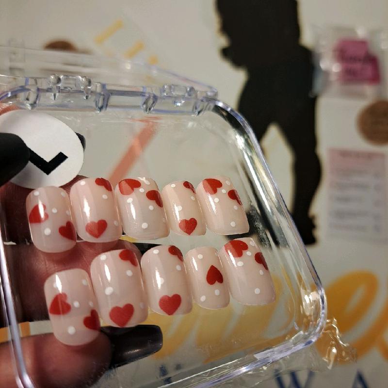 CMW (Dots of Love) press-on nails bring a playful romance to your fingertips. Featuring a nude natural base adorned with white polka dots and red hearts, these short square nails offer a classic yet fun look—exclusively in a size medium only."