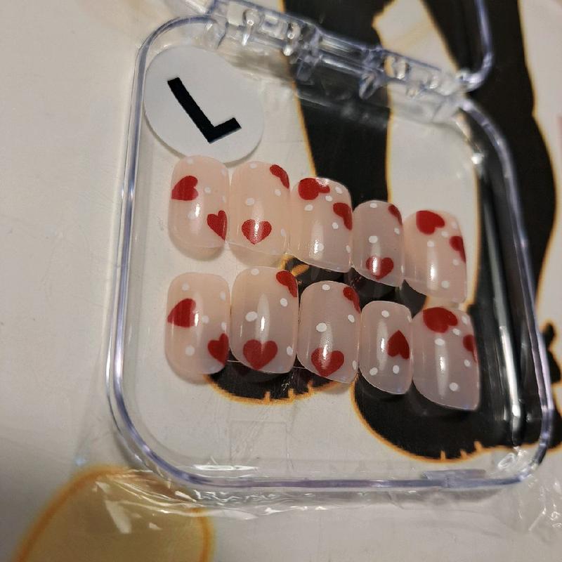 CMW (Dots of Love) press-on nails bring a playful romance to your fingertips. Featuring a nude natural base adorned with white polka dots and red hearts, these short square nails offer a classic yet fun look—exclusively in a size medium only."