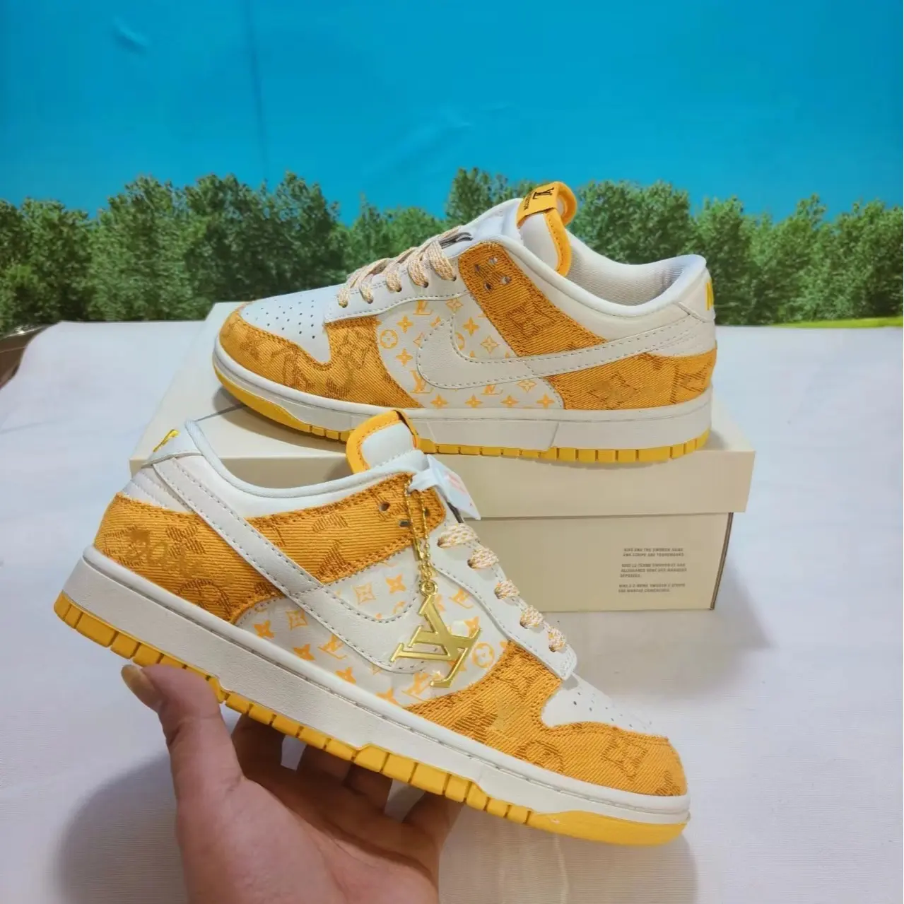 Golden monogram cream patched low-top skate sneakers featuring bright warm yellow rubber sole, dual premium woven textile & smooth leather build, ventilated perforated toe panels, detachable gold charm included