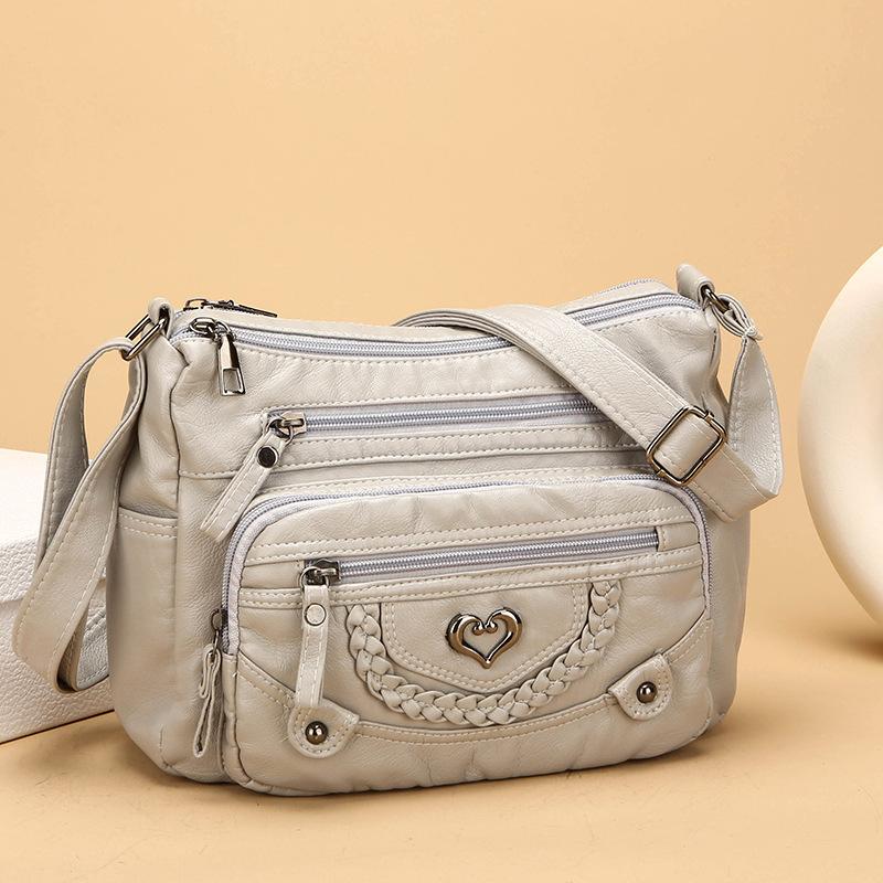 A stylish and soft genuine leather crossbody bag, designed for women, featuring multiple pockets, a heart-shaped pattern, and a spacious interior.  It's fashionable, versatile, and perfect for everyday use.