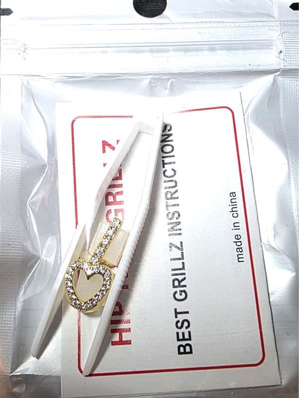 Gold  Plated Hollow Heart Grillz Teeth Jewelry – Gold  Hip Hop Snap-On Tooth Caps. Comes with two pieces  heart and bar tweezers