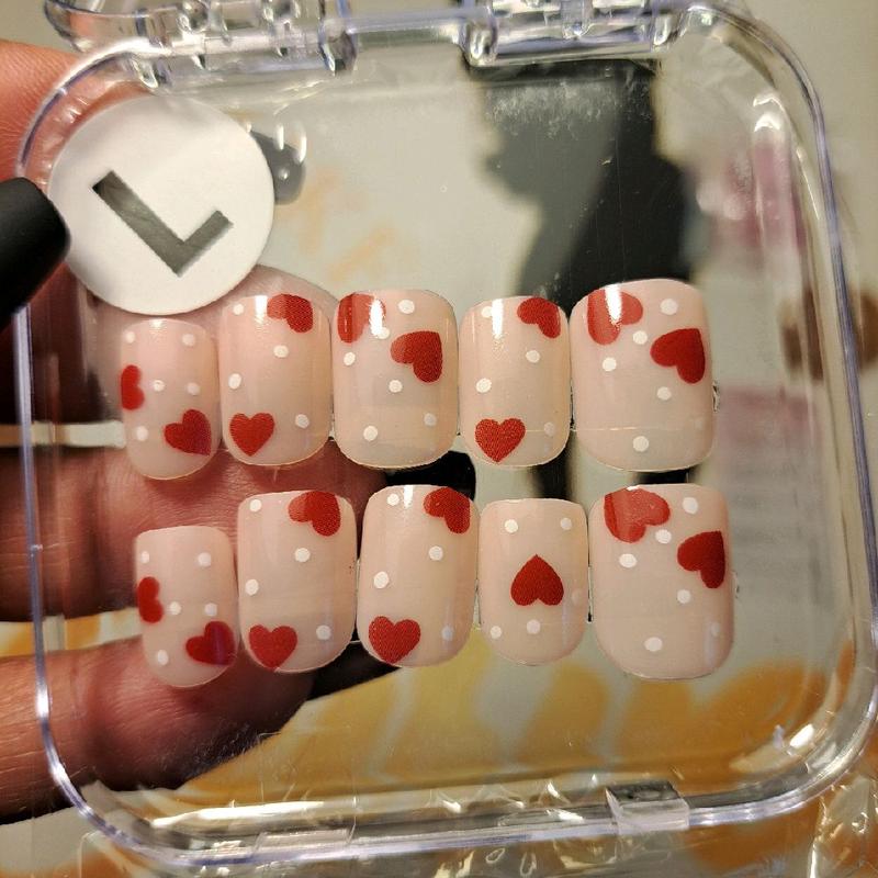 CMW (Dots of Love) press-on nails bring a playful romance to your fingertips. Featuring a nude natural base adorned with white polka dots and red hearts, these short square nails offer a classic yet fun look—exclusively in a size medium only."